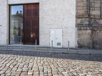 a cobblestone street is near a large old building on a sunny day in the country