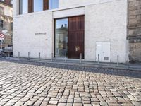 a cobblestone street is near a large old building on a sunny day in the country