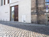 a cobblestone street is near a large old building on a sunny day in the country