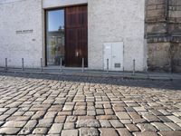 a cobblestone street is near a large old building on a sunny day in the country