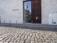 a cobblestone street is near a large old building on a sunny day in the country