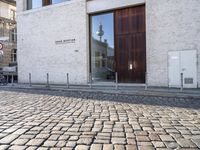 a cobblestone street is near a large old building on a sunny day in the country