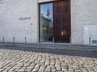 a cobblestone street is near a large old building on a sunny day in the country