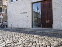 a cobblestone street is near a large old building on a sunny day in the country