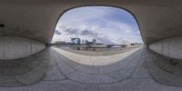 a reflection of a city in the center of a circular mirror on the ground with a person sitting on the floor at the bottom