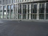 a building with tall windows on a city street with a person on a skateboard