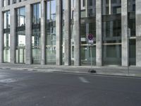 a building with tall windows on a city street with a person on a skateboard