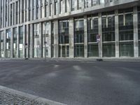 a building with tall windows on a city street with a person on a skateboard