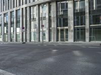 a building with tall windows on a city street with a person on a skateboard