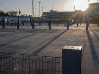the sun is shining on a city square area with benches and gates near an airplane control tower