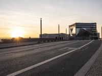 a train sitting on the side of a bridge next to buildings under the setting sun