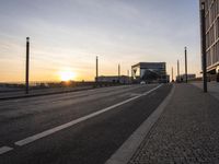 a train sitting on the side of a bridge next to buildings under the setting sun