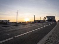 a train sitting on the side of a bridge next to buildings under the setting sun