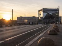 a train sitting on the side of a bridge next to buildings under the setting sun