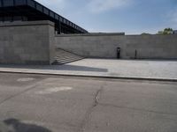 this concrete area contains two steps leading the side of a building to stairs and a large building with concrete walls