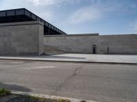 this concrete area contains two steps leading the side of a building to stairs and a large building with concrete walls