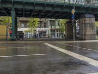 a street under an overpass with a traffic light on it next to a metal barrier