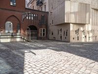 a brick walkway through two red brick buildings with steps leading to it and the door