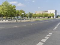 an empty street in front of a building and trees in the middle of the road