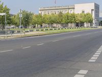 an empty street in front of a building and trees in the middle of the road