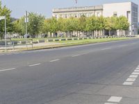 an empty street in front of a building and trees in the middle of the road