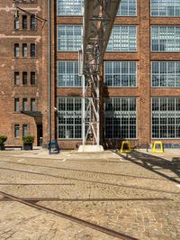 railroad tracks on brick pavement next to a large building with windows on it's sides