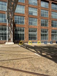 railroad tracks on brick pavement next to a large building with windows on it's sides