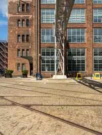 railroad tracks on brick pavement next to a large building with windows on it's sides