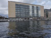 large body of water next to a building near the river with people on it and boats in the water