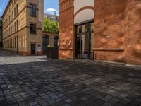 a sidewalk with chairs next to the brick building on the side, some have stairs and some buildings in the background