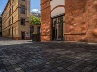 a sidewalk with chairs next to the brick building on the side, some have stairs and some buildings in the background