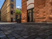 a sidewalk with chairs next to the brick building on the side, some have stairs and some buildings in the background