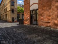 a sidewalk with chairs next to the brick building on the side, some have stairs and some buildings in the background