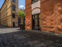 a sidewalk with chairs next to the brick building on the side, some have stairs and some buildings in the background