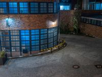 some dark blue windows in an industrial building with no one on the street to the right