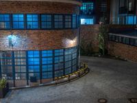 some dark blue windows in an industrial building with no one on the street to the right