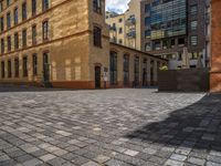 a sidewalk with chairs next to the brick building on the side, some have stairs and some buildings in the background