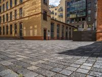 a sidewalk with chairs next to the brick building on the side, some have stairs and some buildings in the background