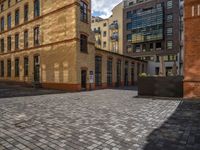 a sidewalk with chairs next to the brick building on the side, some have stairs and some buildings in the background