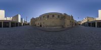 a fish eye lens shot of an empty street with old buildings in the background, and a brick paved road on one side