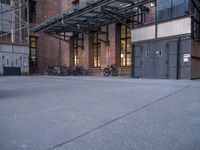 many bikes are parked outside an open building with brick walls and doors to each side