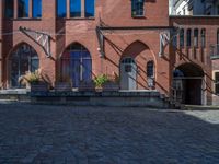 cobblestone driveway surrounded by modern buildings on sunny day with sun reflecting onto the windows