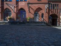 cobblestone driveway surrounded by modern buildings on sunny day with sun reflecting onto the windows