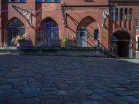 cobblestone driveway surrounded by modern buildings on sunny day with sun reflecting onto the windows