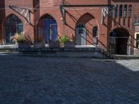 cobblestone driveway surrounded by modern buildings on sunny day with sun reflecting onto the windows