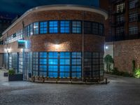 some dark blue windows in an industrial building with no one on the street to the right