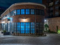 some dark blue windows in an industrial building with no one on the street to the right