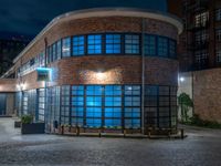 some dark blue windows in an industrial building with no one on the street to the right