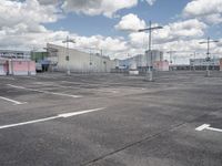 parking lot at an airport with sky in background and buildings in the distance behind the empty parking lot