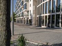 the building is surrounded by many glass panels in the courtyard, and has brick paving in the front